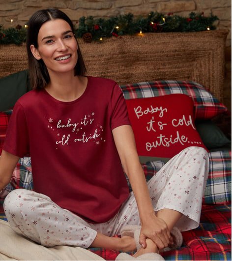 A woman sitting on a bed in red and white festive pyjamas
